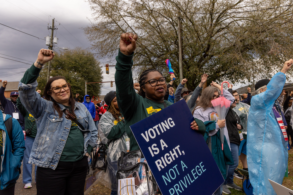 A group of voting rights advocates at the annual Selma Jubilee, one of which is holding a sign that says," Voting Is A Right, Not A Privilege."