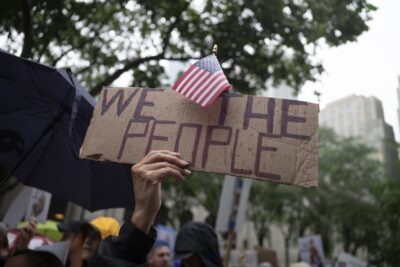 A protester holds up a sign that says "WE THE PEOPLE"