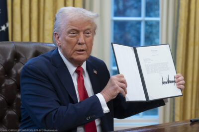 President Donald Trump holds up a recently signed executive order in the Oval Office of the White House.